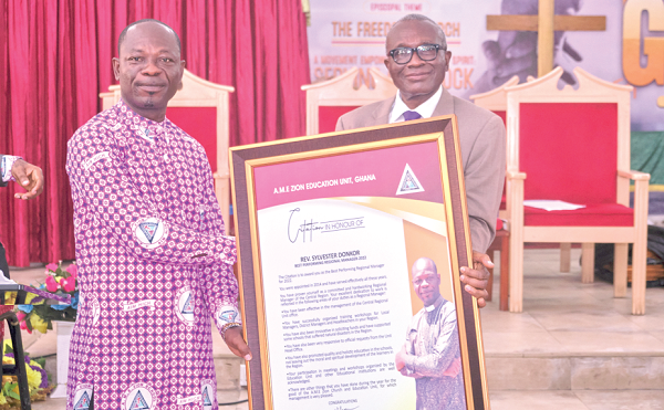 Prof. Joseph Atsu Ayee (right), Chairman of the Education Board of the African Methodist Episcopal Zion Church, Ghana Region, presenting a citation to Rev. Sylvester Donkor, Regional Manager of the Central Regional Education Unit of the AME Zion Church, as best performing regional manager for 2022